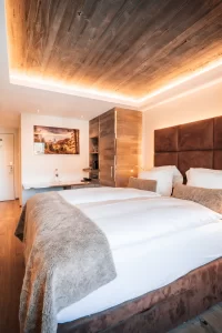 Doppelzimmer Cosy Chic im Hotel Bellerive Zermatt mit Queen-Size-Bett, Holzdecke und indirekter Beleuchtung