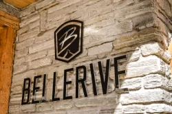 Schwarze Bellerive-Buchstaben und Bergwappen an der Natursteinwand am Eingang des Hotel Bellerive Zermatt.
